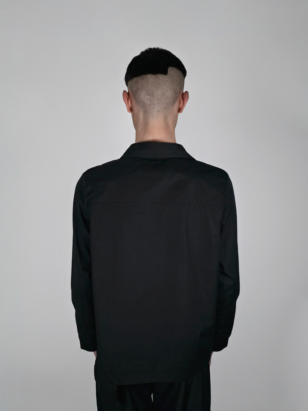 Vue de dos d’un homme portant la chemise en coton Stephen, noire et asymétrique.