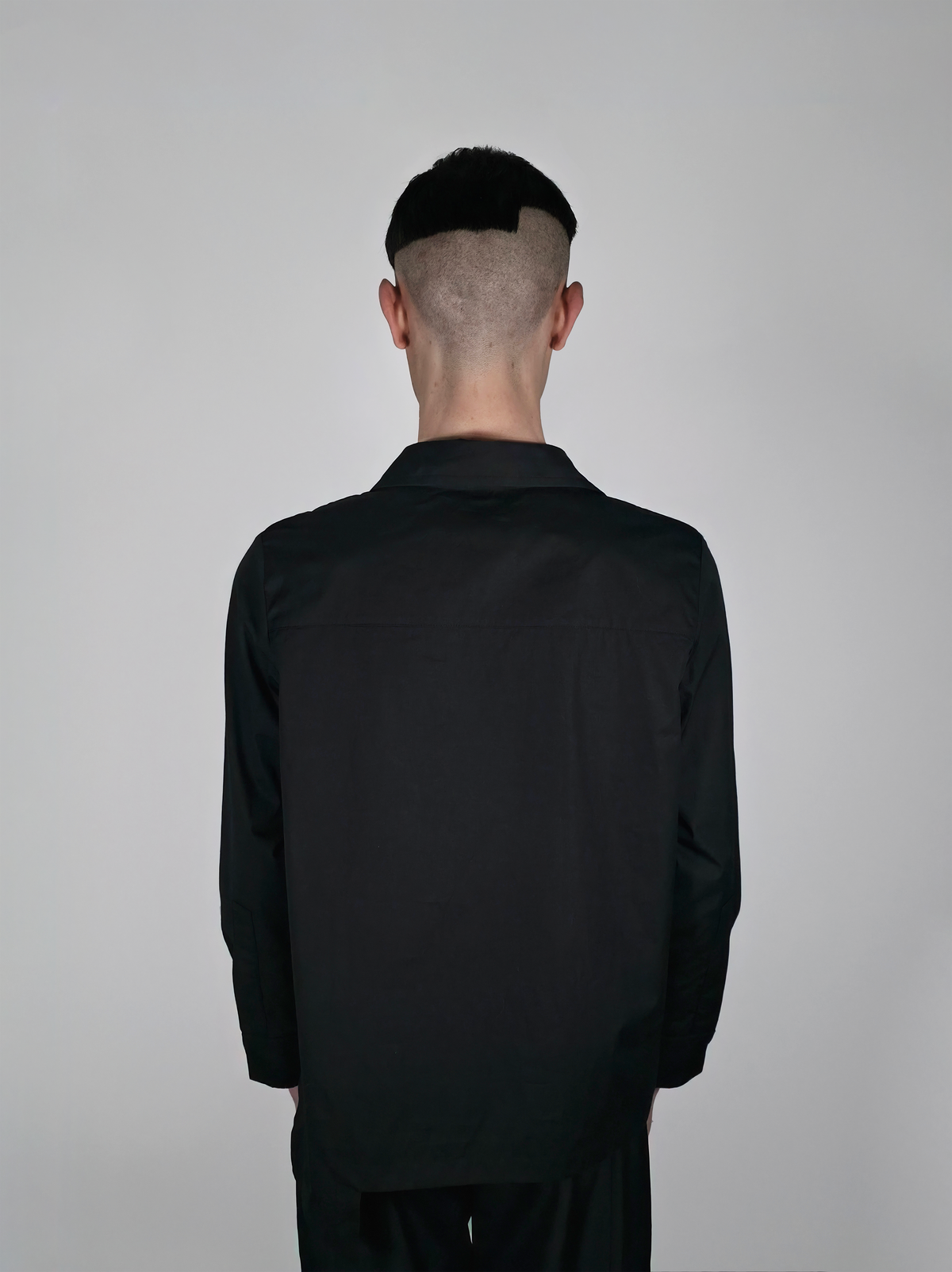 Vue de dos d’un homme portant la chemise en coton Stephen, noire et asymétrique.
