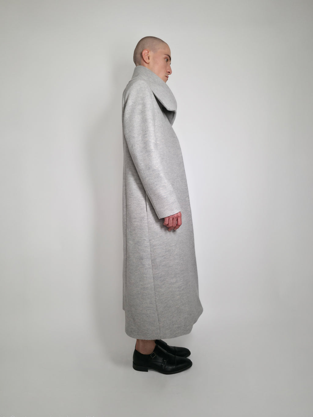 Vue de côté du long manteau Michelle en laine gris sur un Homme avec un grand col.
