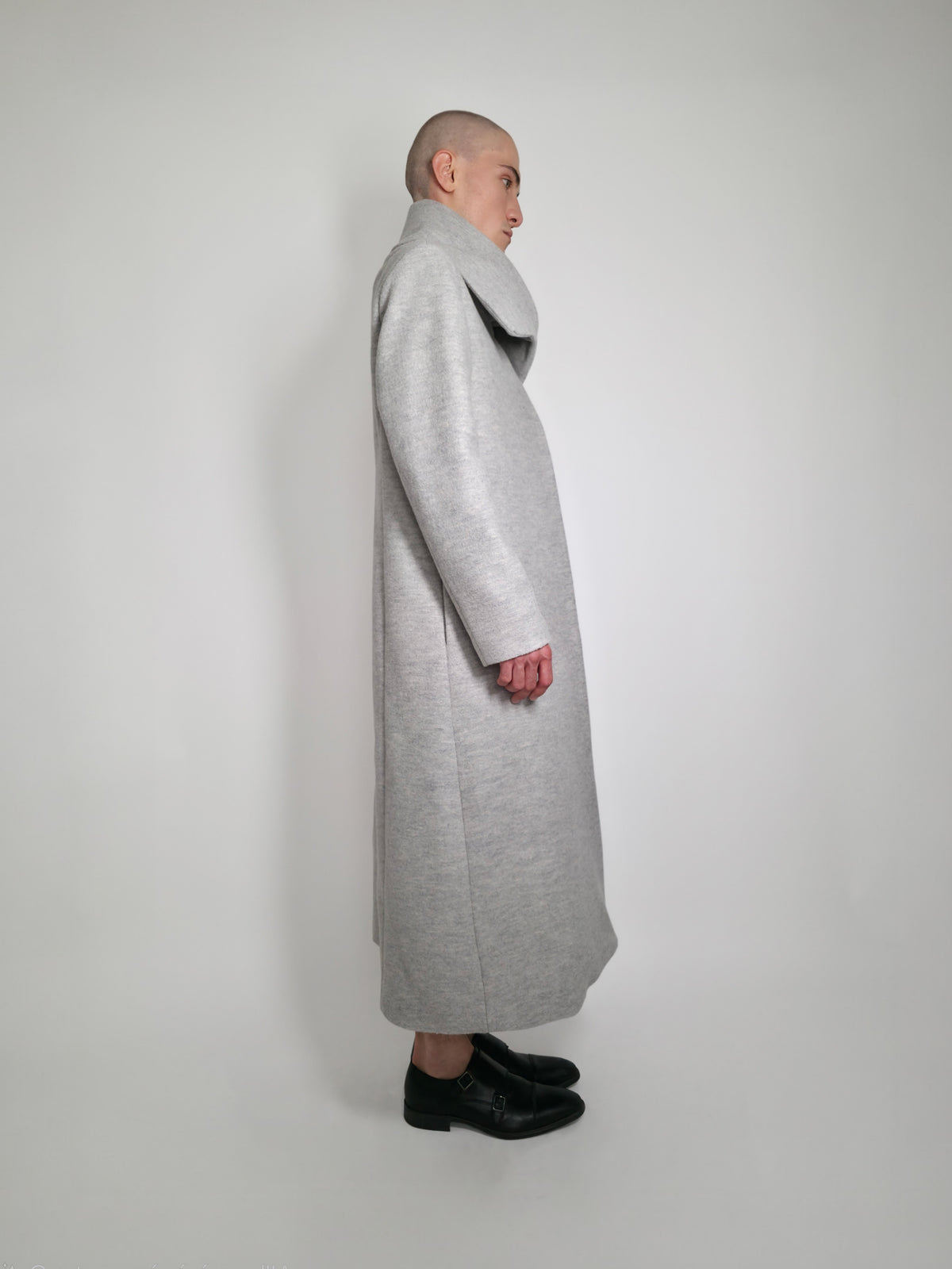 Vue de côté du long manteau Michelle en laine gris sur un Homme avec un grand col.