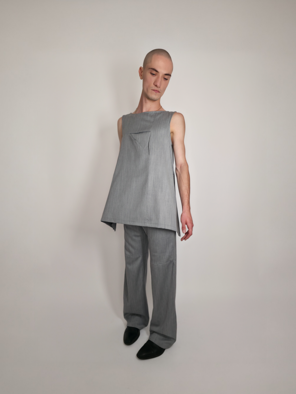 Homme portant la robe Myshellie grise sans manches avec un col bateau, accompagnée du pantalon gris Michael.