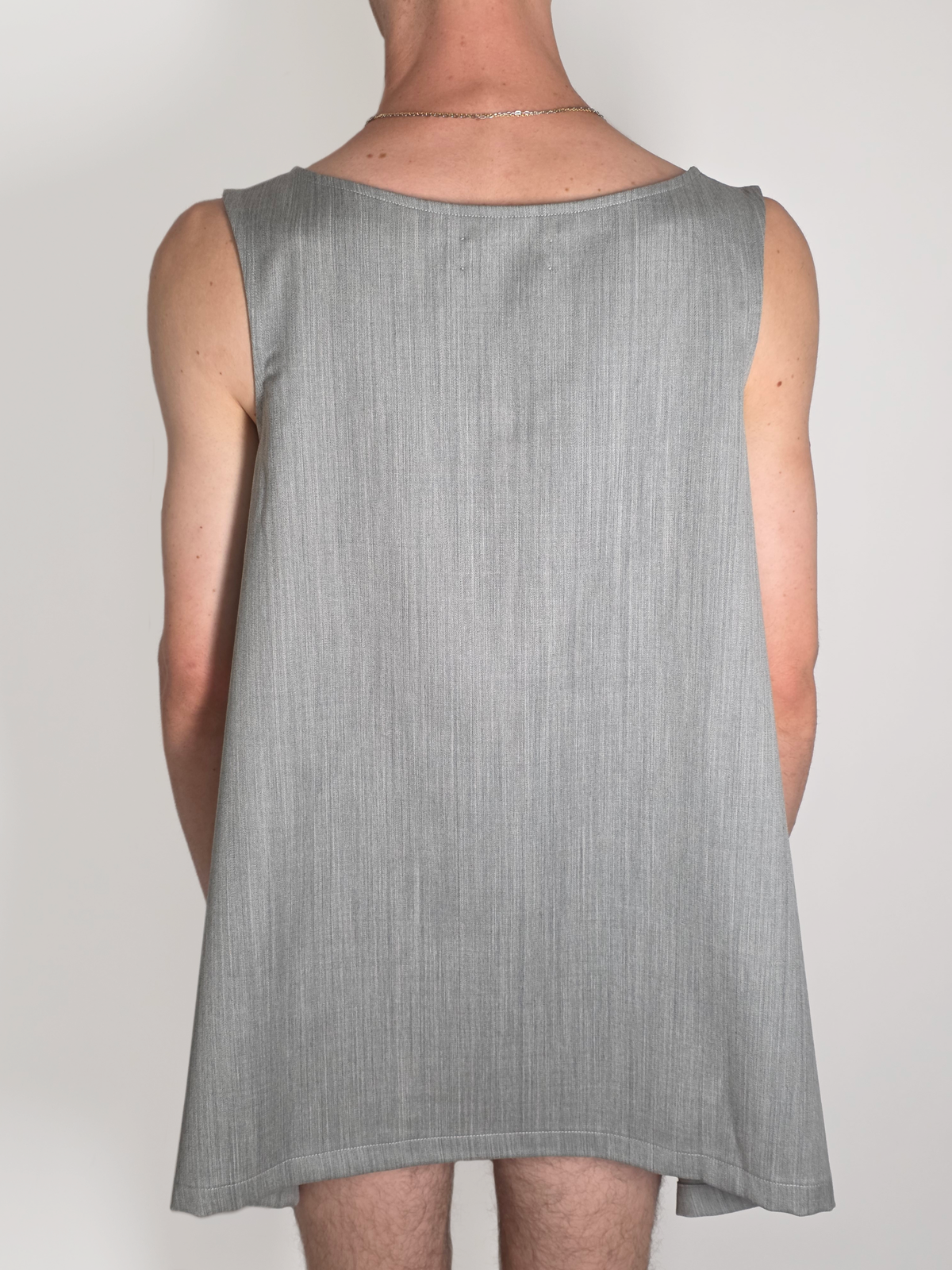 Dos d’un homme portant la robe Myshellie grise courte en laine, sans manches.
