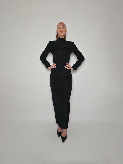 Femme portant la veste cintrée en laine et viscose Tyffaine noire, avec une ouverture sur la poitrine, et le haut Théophanie.