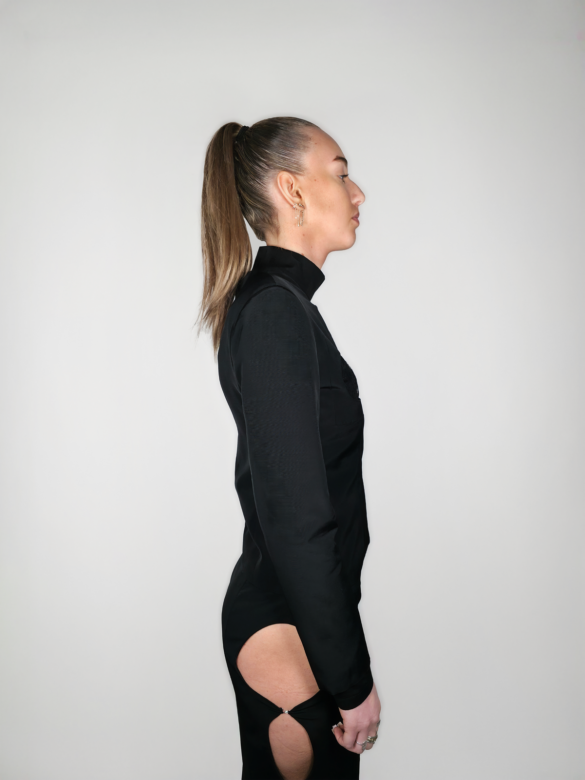 Vue de côté d’une femme portant la veste cintrée en laine et viscose Tyffaine, noire avec la jupe Théphaline.